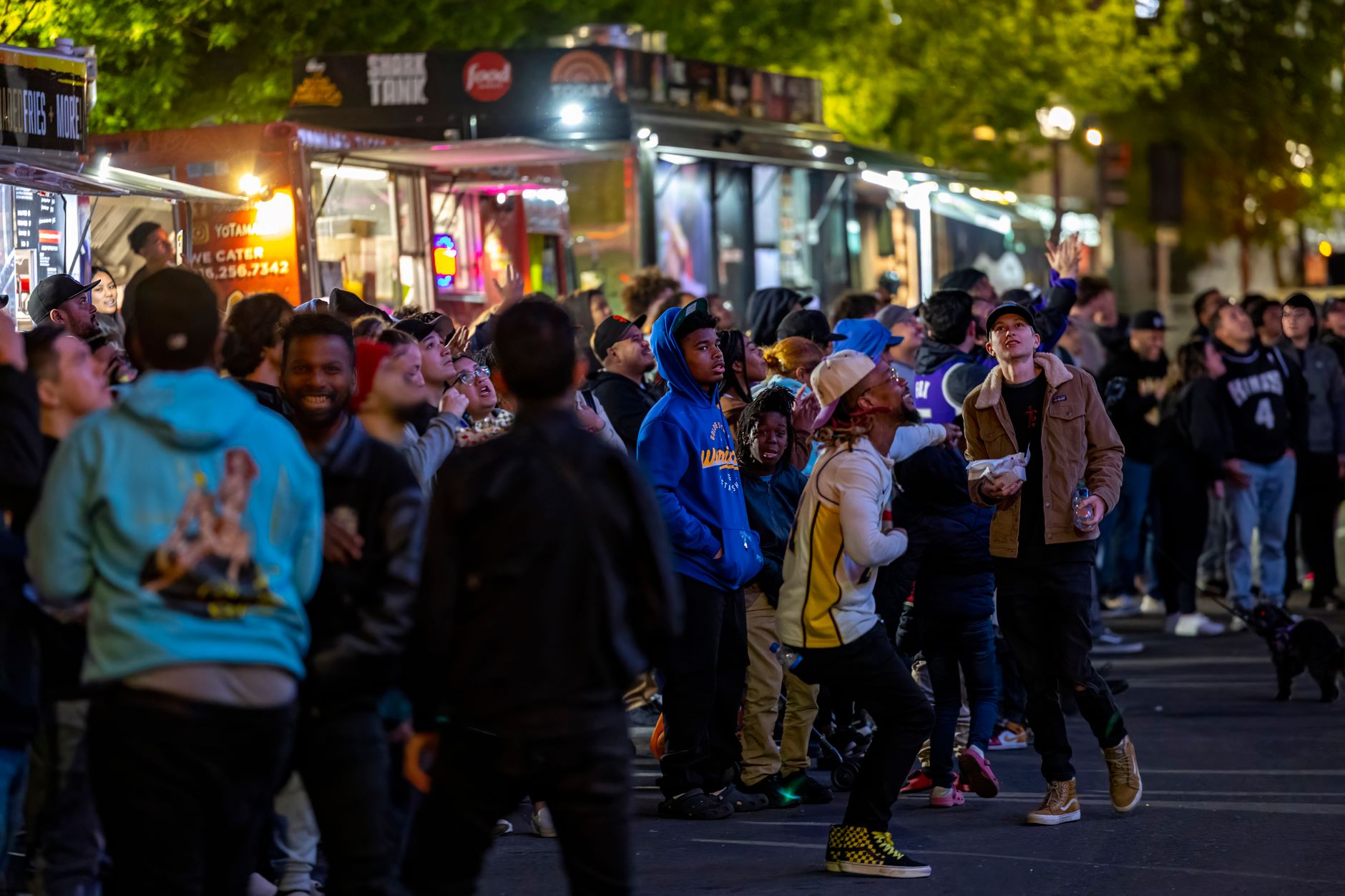 Tłum przechodniów przy kolorowych food truckach nocą