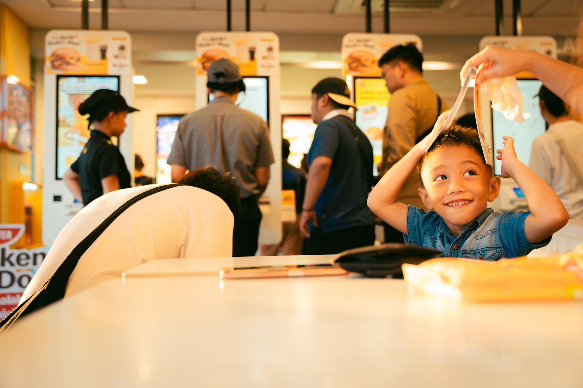 Uśmiechnięty chłopiec bawi się menu w tętniącej życiem restauracji fast food