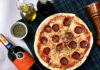 Pizza pepperoni i kieliszki czerwonego wina na kraciastym obrusie