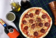 Pizza pepperoni i kieliszki czerwonego wina na kraciastym obrusie