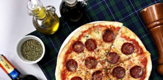 Pizza pepperoni i kieliszki czerwonego wina na kraciastym obrusie