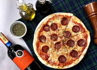 Pizza pepperoni i kieliszki czerwonego wina na kraciastym obrusie