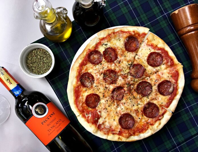Pizza pepperoni i kieliszki czerwonego wina na kraciastym obrusie